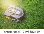 Robotic Lawn Mower cutting grass in the garden. Automatic robot lawnmower in modern garden on sunny day.