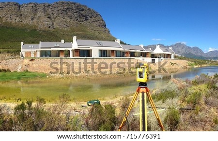Robotic total station instrument set up by a dam with mountains in the background