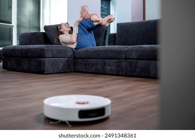 Robotic vacuum cleaner cleaning the living room while mother and son playing. - Powered by Shutterstock