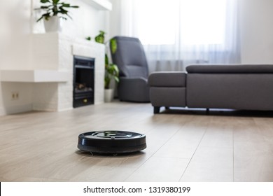 Роботизированный пылесос на ламинатном деревянном полу в гостиной