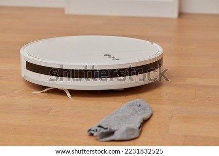 Robotic vacuum cleaner performs cleaning of the room, where socks laying on the floor. Smart cleaning technology