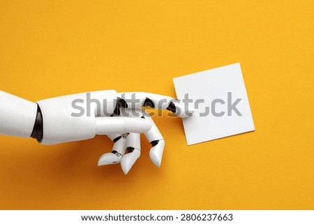 A robotic white hand points for a empty white paper card on a bright yellow background. Concept of artificial intelligence, machine learning and future technology.