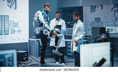 In Robotics Development Laboratory: Engineers and Scientists Work on a Bionics Exoskeleton Prototype with Person Raising Bent Leg. Designing Wearable Exosuit to Help Disabled People, Warehouse Workers
