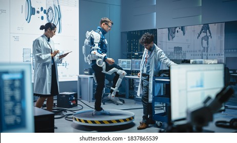 In Robotics Development Laboratory: Engineers and Scientists Work on a Bionics Exoskeleton Prototype with Person Testing it. Designing Wearable Exosuit to Help Disabled People, Warehouse Workers