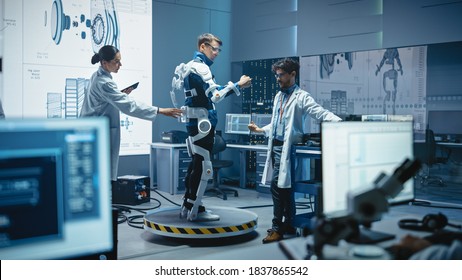 In Robotics Development Laboratory: Engineers And Scientists Work On A Bionics Exoskeleton Prototype With Person Testing It. Designing Wearable Exosuit To Help Disabled People, Warehouse Workers