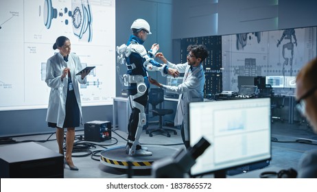 In Robotics Development Laboratory: Engineers And Scientists Work On A Bionics Exoskeleton Prototype With Person Testing It. Designing Wearable Exosuit To Help Disabled People, Warehouse Workers