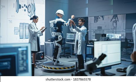 In Robotics Development Laboratory: Engineers And Scientists Work On A Bionics Exoskeleton Prototype With Person Testing It. Designing Wearable Exosuit To Help Disabled People, Warehouse Workers