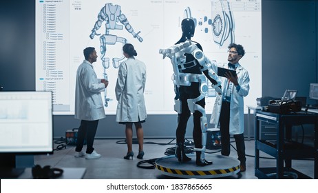 In Robotics Development Laboratory: Female Engineer And Male Scientist Work With Big Screen Showing Robotics Exoskeleton Prototype Design. Building Exosuit To Help Disabled People, Hard Labor Workers