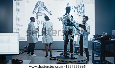 In Robotics Development Laboratory: Female Engineer and Male Scientist Work With Big Screen Showing Robotics Exoskeleton Prototype Design. Building Exosuit to Help Disabled People, Hard Labor Workers