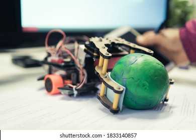 Robotics electronics in laboratory in school, STEM Education for Learning, Hands student on Electronic board. Kids robot holding model globe by coding programming, IOT technology innovation classroom