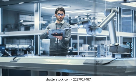 Robotics Engineer Researching and Developing a Technological Robot Arm Project, Standing with Tablet Computer in Scientific Technology Lab. Young Male Working on an AI Robotic Arm. - Powered by Shutterstock