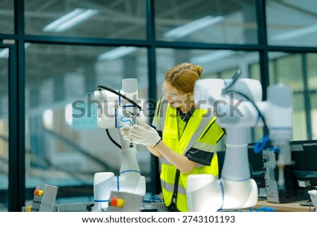A robotics engineer uses a tablet to program a robot with a machine vision system, while her colleague calibrates the end-of-arm tooling on another unit in a system integration lab.