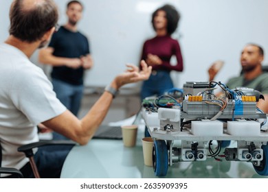Robotics engineers testing and discussing a prototype of a robot in a modern laboratory during a meeting