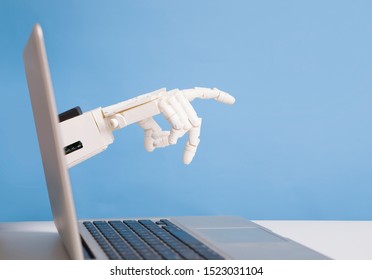 Robotics Invasion Into Real Life. Robot Hand Reaching Out Of Laptop Screen, Blue Background