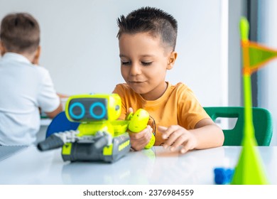 Robotics programming class. Preschool Children construct and code Robot. STEM education using constructor blocks and laptop, remote control joystick. Technology educational development for school kids