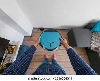 Robots Takeover, Robots As Pets And Evil Robots Concept. Man Holding A Robot Vacuum Cleaner With Eyes And Teeth.