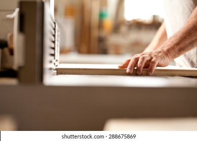 Robust Hands Of A Man Working On A Wood Shaper (spindle Moulder) In A Carpenter Workshop, Detail Of The Hand Holding A Board