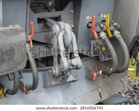 The robust iron linkage system connects railway cars securely while pressure hoses enable braking controls, showcasing essential engineering components for reliable cargo operations