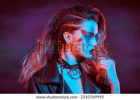 Rock accessories. Rock and Pop music. Close-up of a rock star girl with bright glitter makeup and hair in glam rock style in colored stage lighting.