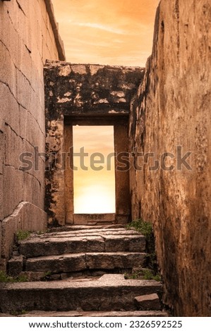 Rock Architecture Narrow ancient old street with stone steps to an open rock door with an open sky sunset, Hampi, India