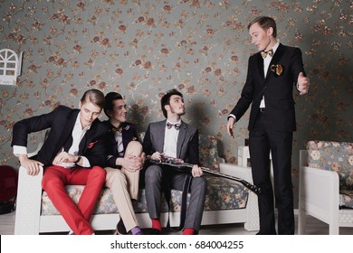 Rock Band Of Four Men In Classic Suits Laugh, Have Fun, Talk In Their Room With Electric Guitars Listen To Their Manager