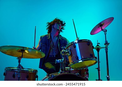 Rock band live concert. Young man in stylish clothes, musician playing drums against blue background in neon light. Concept of music, talent show, performance, concert, festival, instruments, youth - Powered by Shutterstock