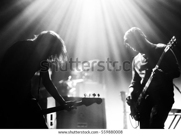 Rock band on\
a stage playing in a backlights, black and white silhouettes with\
the beautiful stage lights