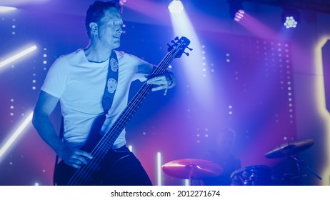 Rock Band Performing at a Concert in a Night Club. Portrait of a Lead Guitarist Playing on a Guitar. Live Music Party in Front of Bright Colorful Strobing Lights on Stage.