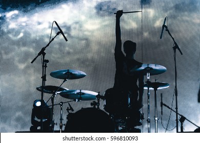 Rock band performs on stage. Musician drummer silhouette in the concert. silhouette of drum player in action on stage in front of concert crowd.