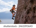 rock climber boy. child is practicing rock climbing. summer camp. sport in nature. cute teenager climbing on a rock with belay, sport people lifestyle concept