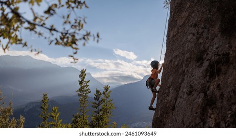 rock climber boy. child is practicing rock climbing. summer camp. sport in nature. cute teenager climbing on a rock with belay, sport people lifestyle concept - Powered by Shutterstock