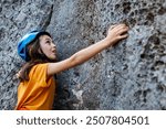 rock climber boy. a boy in a helmet climbs a rock. a child is rock climbing at a summer camp. sport in nature. rock climbing.
