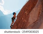 rock climber boy. sport in summer camp. a child is rock climbing at a summer camp. sport in nature on a sunny day. cute teenager climbs a rock with a belay. active holidays. summer rest.
