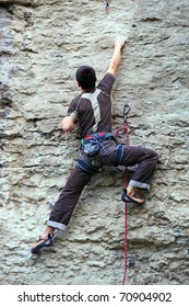 Rock Climber Climbing Up A Cliff