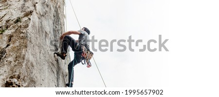 Rock climber climbing a vertical wall wall in the mountain. risk sport. mountain activity. image with large copy space