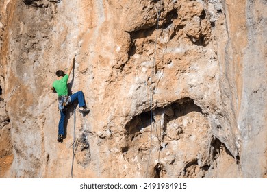 A rock climber climbs to the top along a difficult route. - Powered by Shutterstock