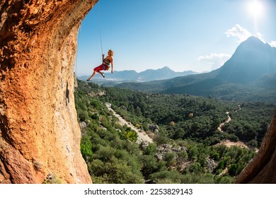 Rock climber descends from the route, the climber hangs on a rope, a rock in the form of an arch, climbing routes in a cave, a girl rides on a rope