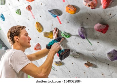 Rock climber fastens the hook with a screwdriver at the climbing wall in the boulder hall - Powered by Shutterstock