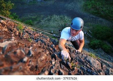 A Rock Climber Looking Up And Grabbing A Hold Of The  Stone Wall