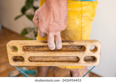 rock climber male hand holding finger strength training board with two fingers. climbing workout at home. rock climber's hand close-up. fingerboard and hangboard
 - Powered by Shutterstock