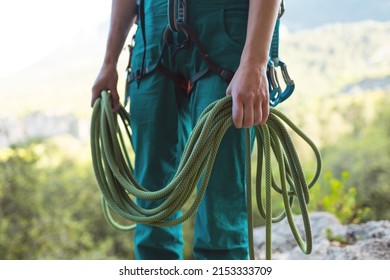 A rock climber prepares equipment for climbing, a woman holds a rope in her hands, a climber coils a rope - Powered by Shutterstock