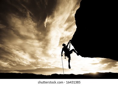 A rock climber is silhouetted against the evening sky as he rappels past an overhang in Joshua Tree National Park. - Shutterstock ID 16431385