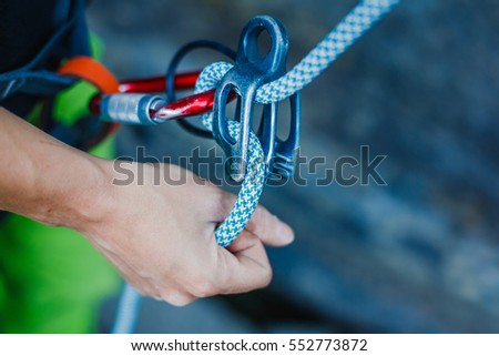 Rock climber wearing safety harness and climbing equipment outdoor, close-up image
