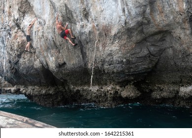 Rock Climbing (deep Water Solo) In Thailand. Two Climbers (men) Climb The Rock Above The Sea. 