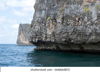 Rock Climbing (deep Water Solo) In Thailand. Climber (girl) Climbs The Rock Above The Sea. 