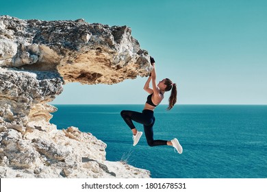 Rock Climbing. Sport. Active Lifestyle. Athlete Woman Hangs On Sharp Cliff. Seascape. Outdoors Workout. High Resilience