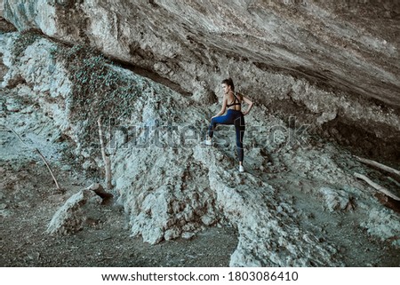 Beautiful young woman thinking and sitting on the rocks outdoors on the countryside