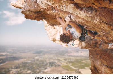 Rock Climbing Sports And Man On Mountain Cliff For Outdoor Fitness, Wellness Goal Or Workout Motivation. Adventure, Healthy Energy Of Strong Athlete Bouldering In Safety Gear, Rope On Blue Sky Nature