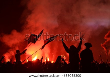 A rock concert in Russia. The outlines of the audience, flags in the light of fireworks. A bright red glow