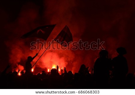 A rock concert in Russia. The outlines of the audience, flags in the light of fireworks. A bright red glow